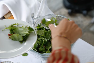 The person with green leaves on the white ceramic plate
